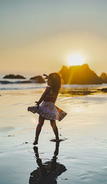 Cute girl dancing on beach during sunset