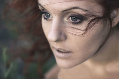 Close-up of a young redhead woman in the nature with an enchanted gaze