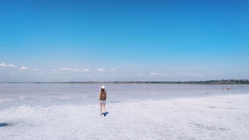 Rear view of woman on beach against sky