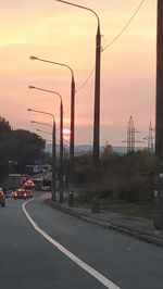 Cars on street against sky during sunset