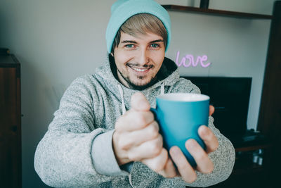Portrait of man holding coffee cup at home