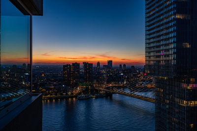 Illuminated buildings in city against sky during sunset