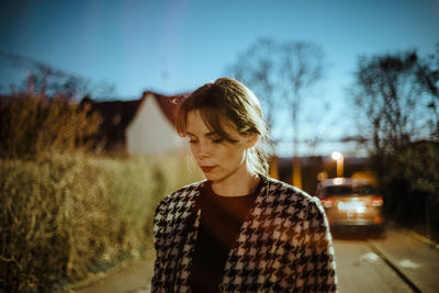 Portrait of teenage girl standing by tree against sky