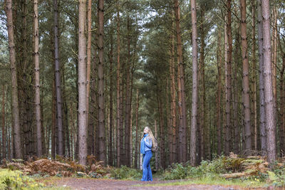 Woman standing with backpack near trees in cannock chase forest