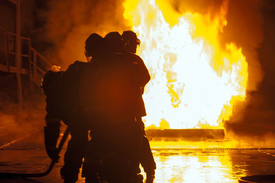 Rescue workers dousing fire at night