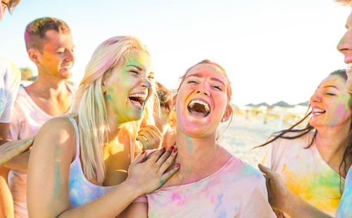 Friends celebrating holi with powder paint at beach