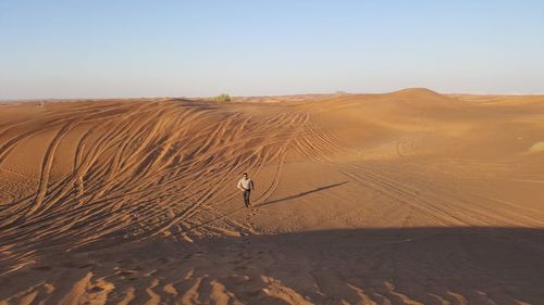 High angle view of mature man running on desert against clear sky