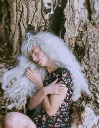 Man in dress and gray wig sleeping in forest