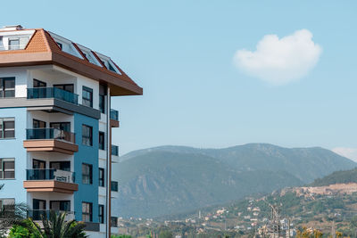 Part of an apartment building against the backdrop of a mountain and blue sky in turkey.