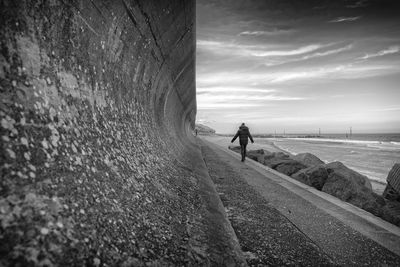 People walking on beach by sea against sky