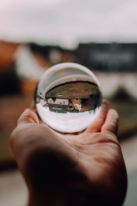 Close-up of hand holding glass against sky