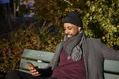 Man sitting on bench and using phone in autumn park