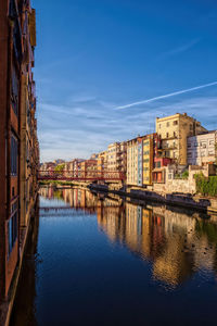 Canal amidst buildings in city against blue sky