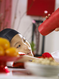 Close-up of teenage boy in traditional clothes looking through paper