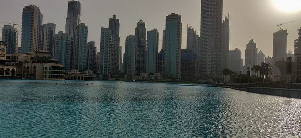 Modern buildings by swimming pool in city against sky