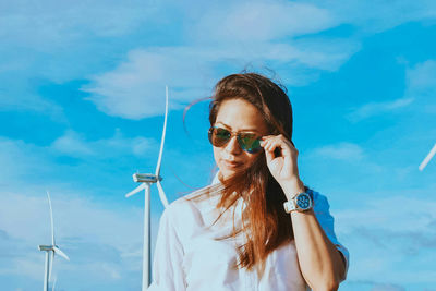 Young woman wearing sunglasses against blue sky