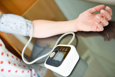 Midsection of woman by blood pressure gauge on table