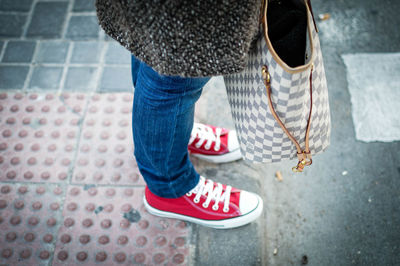 Low section of woman with bag standing on footpath