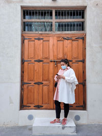 Portrait of young woman standing against wall