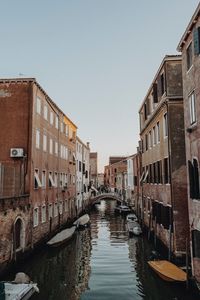 Canal amidst buildings against clear sky