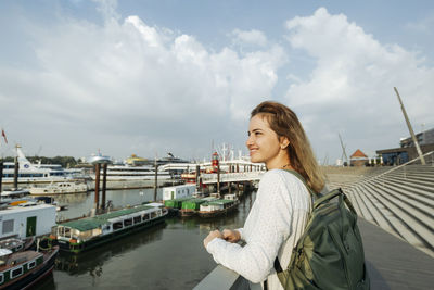 Happy woman standing by railing looking at port of hamburg, germany