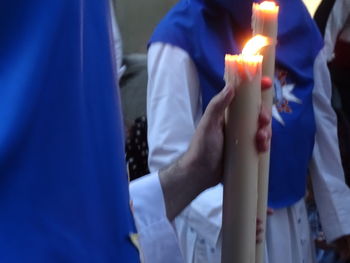 Close-up of hand holding burning candle
