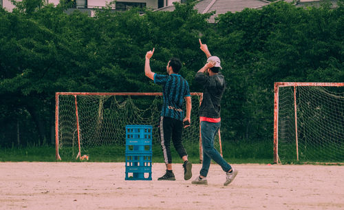 Men standing by plants against trees