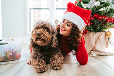 Portrait of young woman with dog on floor at christmas day