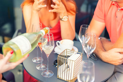 Midsection of people holding drink on table