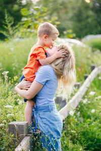 Cute boy kissing mother in field