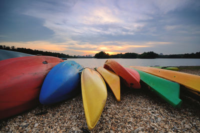 Boats moored on shore against sky during sunset