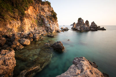 Rocks on sea shore against sky