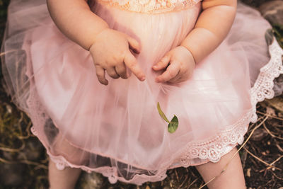 Midsection of baby holding pink flower