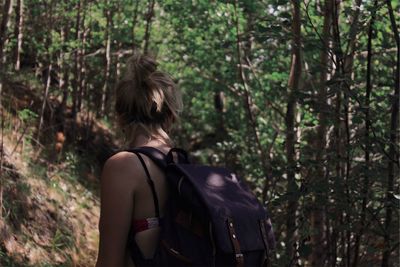 Rear view of woman with backpack standing in forest