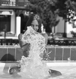 Portrait of sensuous woman splashing water in swimming pool