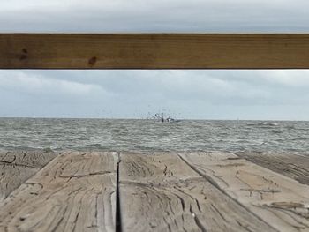 Close-up of wooden jetty by sea against sky