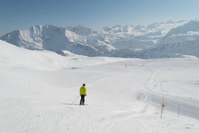 Man skiing on snowcapped mountain against sky