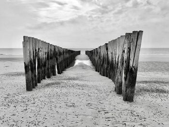 Wooden posts on beach against sky