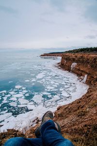 Low section of man by sea against sky