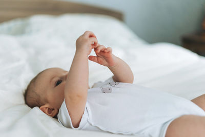 Cute baby girl 2-4 month on bed with white linen, natural tones, selective focus