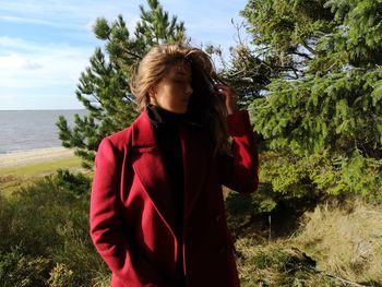 Young woman standing by tree