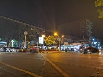 City street by illuminated buildings at night