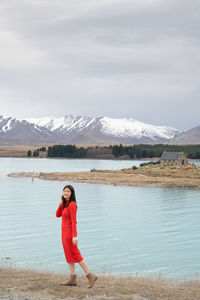 Asian female tourist pose at turquoise color lake tekapo with snowcapped mountain at the background