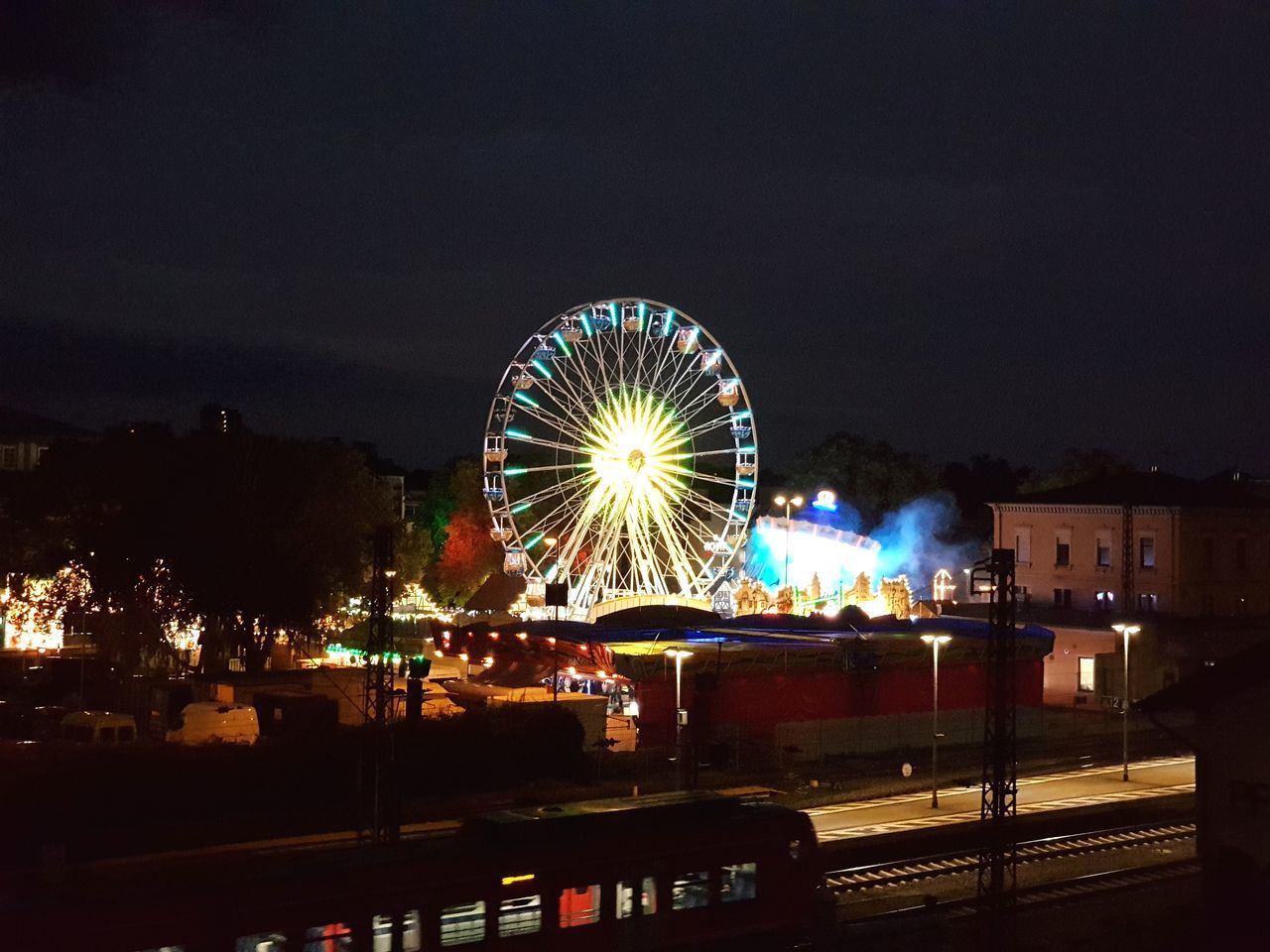 ILLUMINATED FERRIS WHEEL IN CITY AT NIGHT