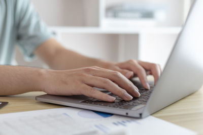 Midsection of woman using laptop on table