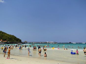 Group of people on beach against clear sky
