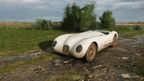 Abandoned car on field against sky