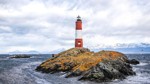 Lighthouse by sea against sky