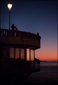 Low angle view of lookout tower by beach during sunset