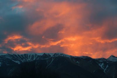 Scenic view of snowcapped mountains against orange sky